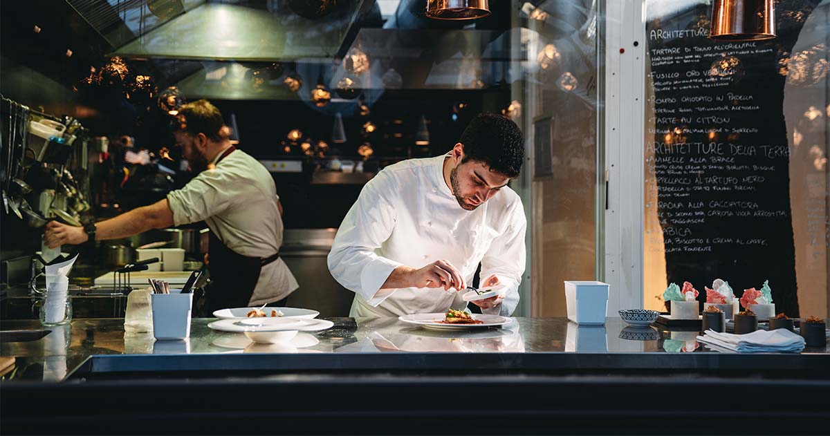 A busy restaurant with a chef working on a meal.