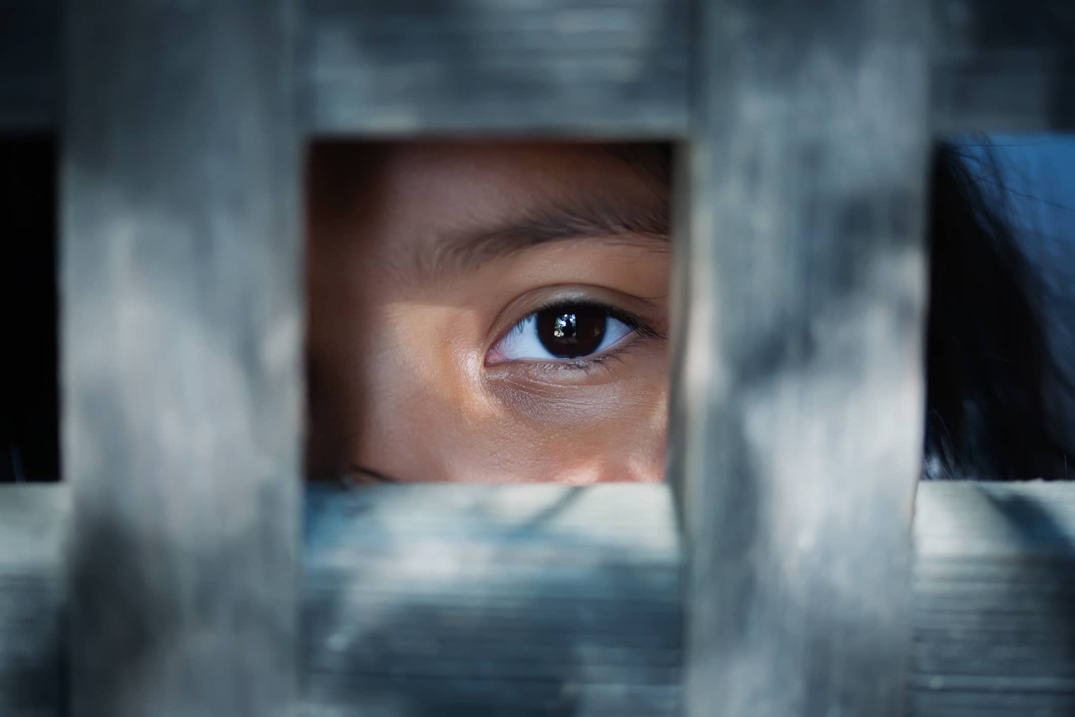 young person looking through grate, close up on eye