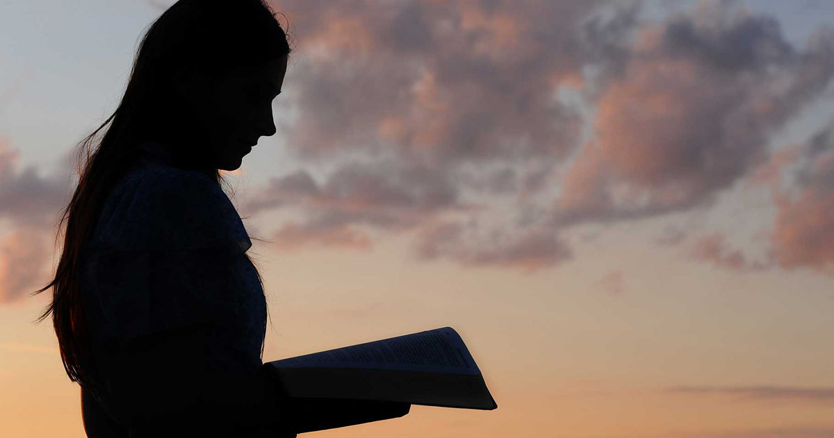 Religious person studying scripture in the twilight.