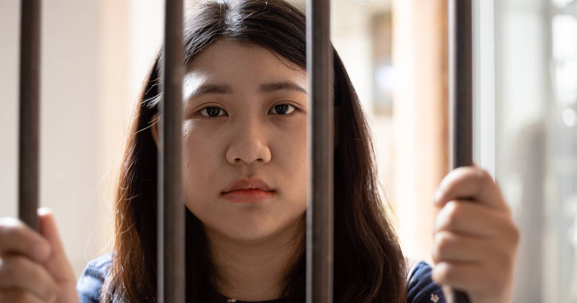 young girl standing behind bars