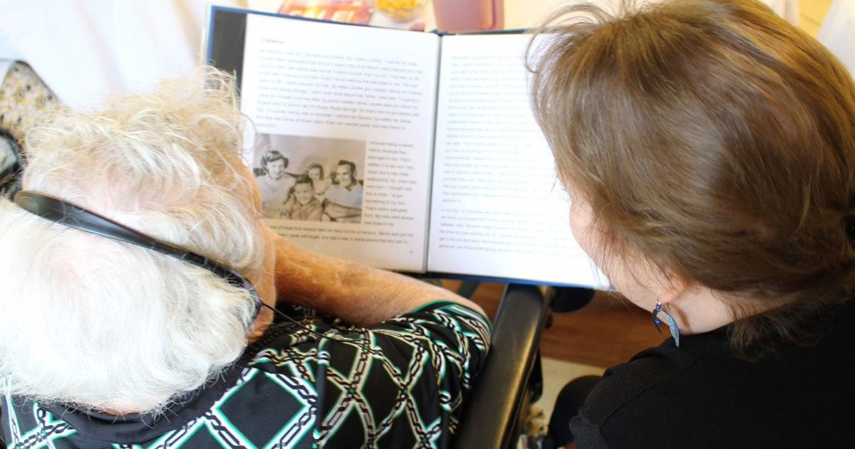 Researcher reading with nursing home patient